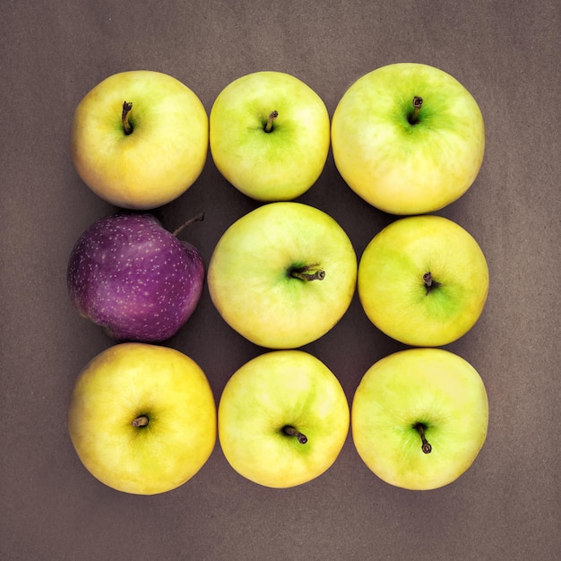 Reife saftige gelbgrüne Äpfel im Quadrat mit einem violetten Apfel
