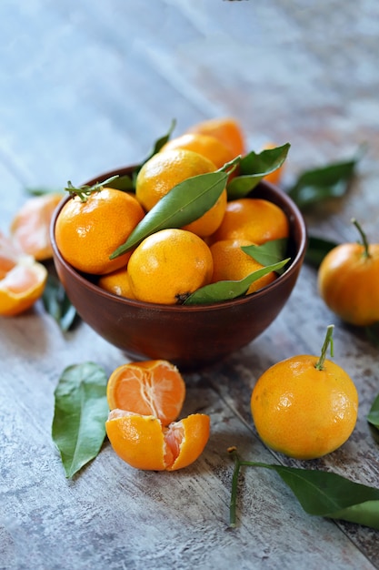 Reife saftige Mandarinen in einer Schüssel. Mandarinenblätter. Frisch duftende Mandarinen. Mandarinen ernten.