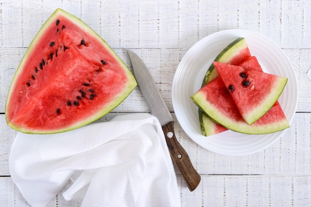 Reife saftige rote Wassermelonenscheiben auf einem Teller auf weißem Holzhintergrund