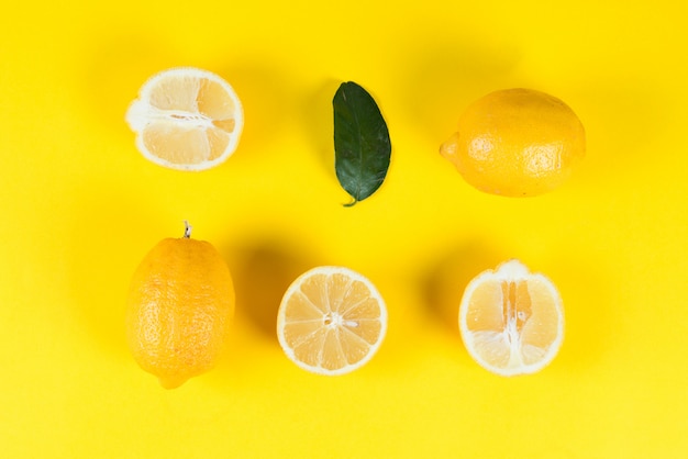 Reife saftige Zitronen mit Blättern auf einem farbigen gelben Hintergrund, kreative flache Lage, Draufsicht