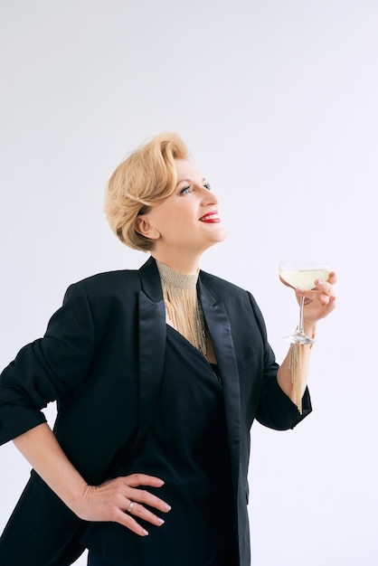 Reife, stilvolle, elegante Frau im Smoking mit einem Glas Sekt