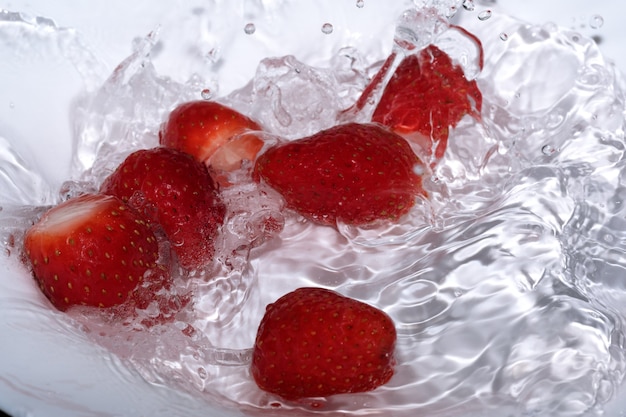 Reife süße frische Erdbeere wird in sauberem kaltem Wasser mit Spritzern und Blasen in Nahaufnahme gewaschen
