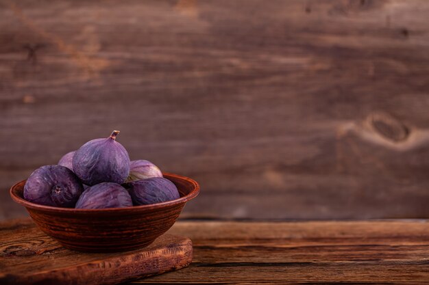 Reife süße violette Feigen in der Weinleseschüssel, Holztisch, Konzept der Bonbons des strengen Vegetariers