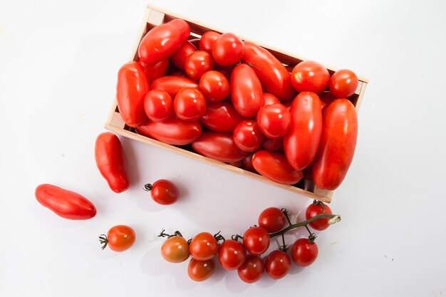 Reife Tomaten liegen in einer Holzkiste auf weißem Hintergrund