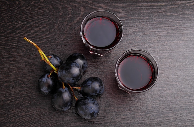 Reife Trauben, Rotwein und ein Glas auf schwarzem Hintergrund