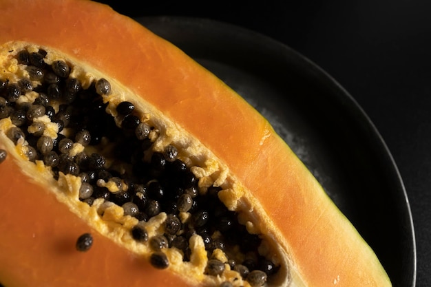 Reife und frisch geschnittene Papaya. Frische und tropische Früchte mit dunklem Hintergrund