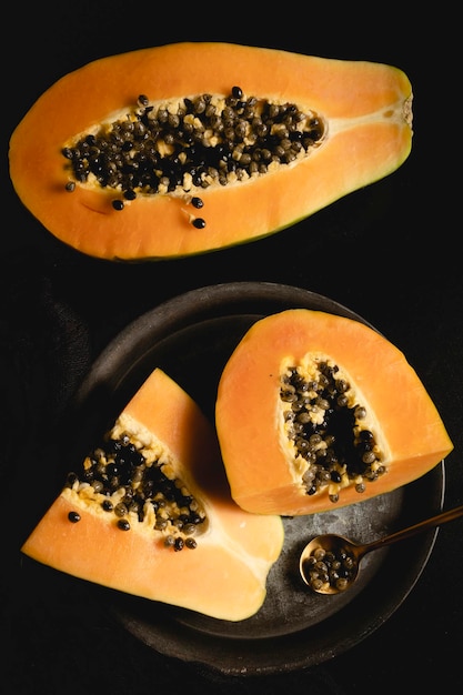 Reife und frisch geschnittene Papaya. Frische und tropische Früchte mit dunklem Hintergrund