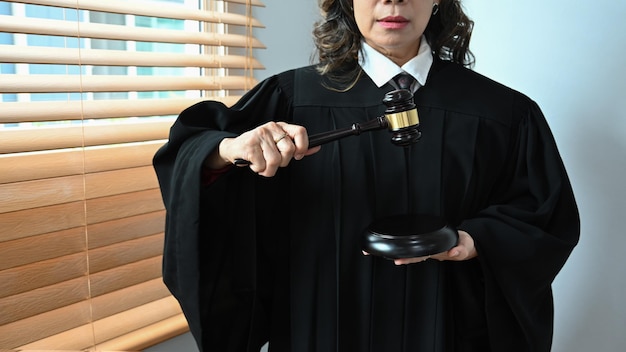 Foto reife weibliche richterin, anwältin oder anwältin, gekleidet in robenkleiduniform mit hammerhammerhammer konzept für recht und gerechtigkeit