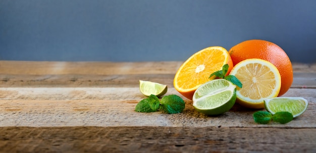 Reife Zitrusfrüchte auf dem alten Holztisch. Orange, Limette, Zitronenminze. Gesundes Essen. Sommer Hintergrund.