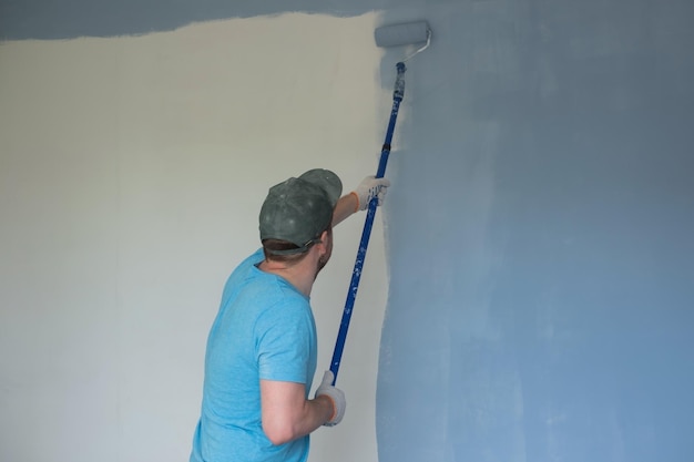 Reifer Arbeiter beim Streichen von Wänden mit einer Walze während der Wohnungsrenovierung