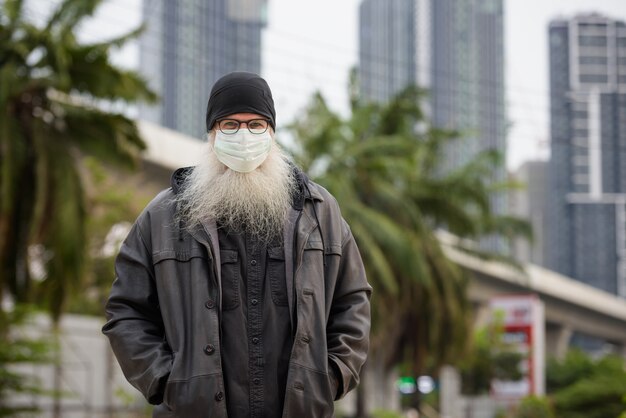 Reifer bärtiger Hipster-Mann mit Maske zum Schutz vor Ausbruch des Koronavirus