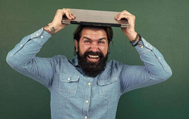 Reifer bärtiger Mann Lehrer im Schulklassenzimmer mit Online-Bildung an der Tafel