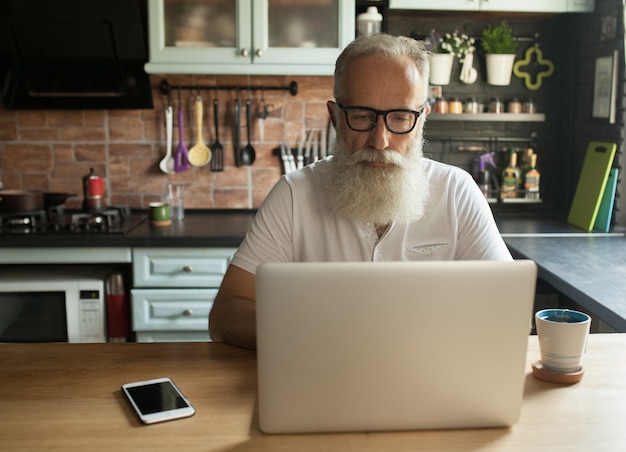 reifer bärtiger Mann mit Laptop und Brille