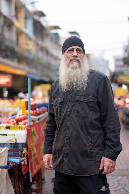 Reifer bärtiger Touristenmann mit Brillen, die in Chinatown denken