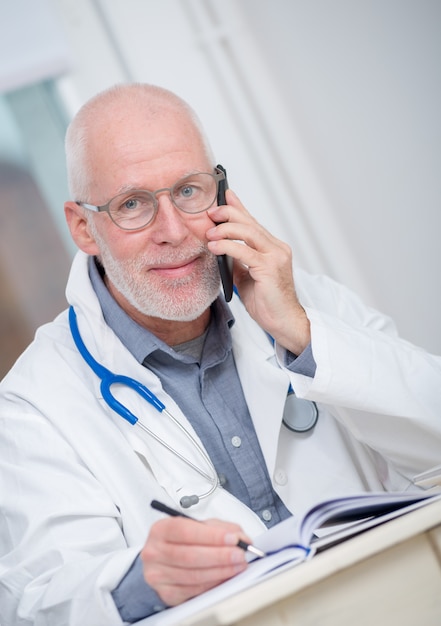 Reifer Doktor am Telefon in seinem Büro