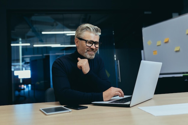 Reifer erfolgreicher Chef, der in einem modernen Büro arbeitet. Senior grauhaariger Geschäftsmann bei der Arbeit