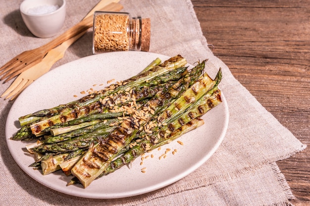 Reifer gegrillter Spargel. Holzbesteck, gesundes Lebensmittelkonzept. Trendiges hartes Licht, dunkler Schatten. Vintage Bretter Tisch, Textfreiraum