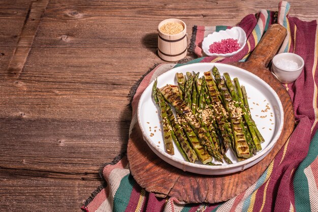 Reifer gegrillter Spargel. Rustikale Anordnung, gesundes Lebensmittelkonzept. Trendiges hartes Licht, dunkler Schatten. Vintage Holzbretter, Textfreiraum