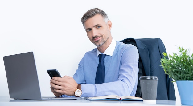 Reifer Geschäftsmann, der im Büro mit Telefon und Laptop arbeitet