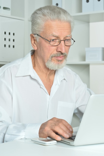 Reifer Geschäftsmann, der mit Laptop im Büro arbeitet