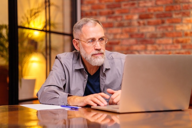 Reifer Geschäftsmann, der spät in der Nacht am Laptop arbeitet