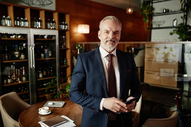 Reifer Geschäftsmann im Anzug steht im Café