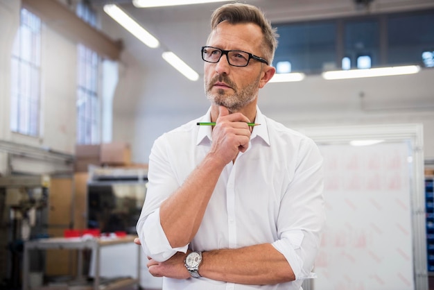 Reifer Geschäftsmann im Fabrikdenken