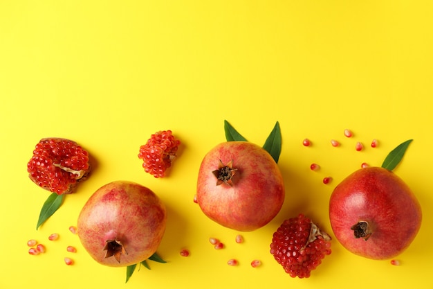 Reifer Granatapfel, Blätter und Samen auf gelbem Hintergrund