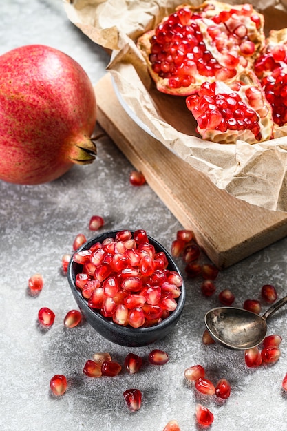 Reifer Granatapfel und Samen auf einem hölzernen Schneidebrett. Bio-Obst. Grauer Hintergrund. Draufsicht