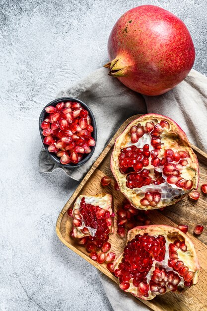 Reifer Granatapfel und Samen in einer Holzschale. Bio-Obst. Grauer Hintergrund. Draufsicht