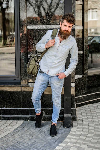 Reifer Hipster mit Bart Bärtiger Mann, der auf der Straße spaziert, moderne männliche Mode, bereit für Abenteuer, brutaler kaukasischer Hipster mit Schnurrbart im urbanen Stil, Urlaubsentdeckung, Wanderkonzept