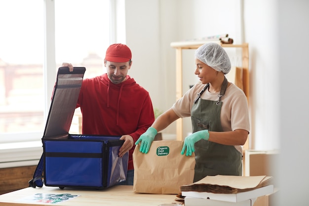 reifer Lieferbote, der Bestellungen zur Kühlbox beim Lebensmittellieferservice verpackt