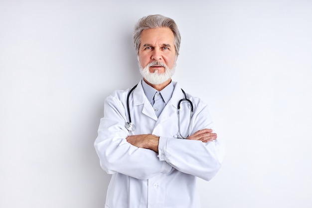 Reifer männlicher Arzt mit Stethoskop lokalisiert auf weißem Studioraum