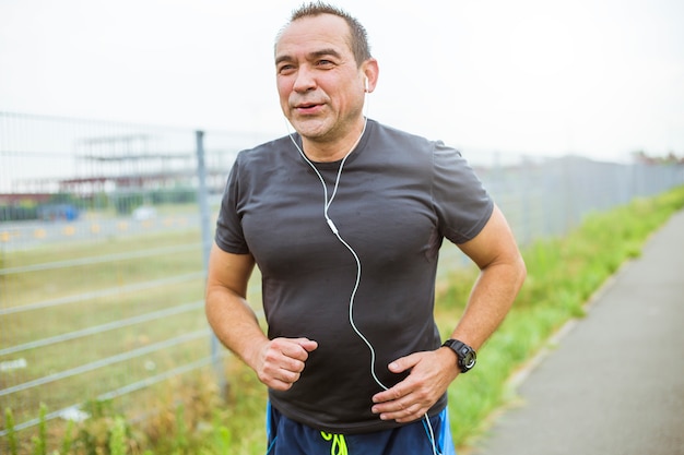 Reifer Mann, der das Rütteln auf einer Stadtstraße tut. Älterer Mann führt einen gesunden und aktiven Lebensstil, der Sport spielt.