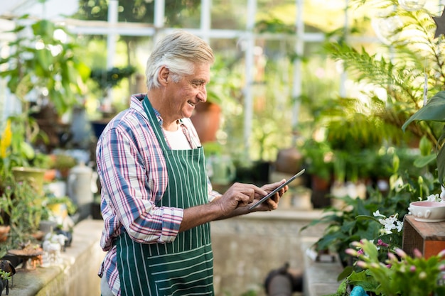 Reifer Mann, der digitale Tablette am Gewächshaus verwendet