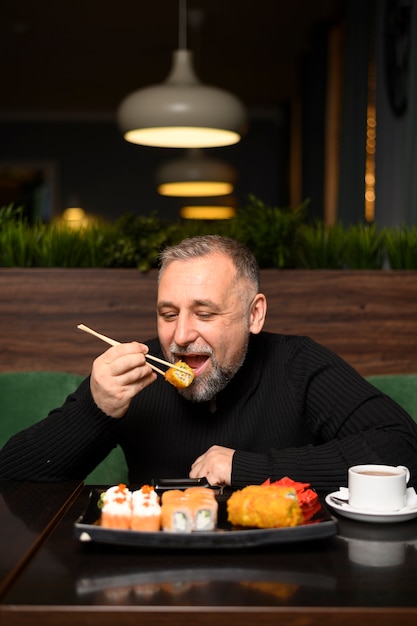 Foto reifer mann, der etwas sushi isst