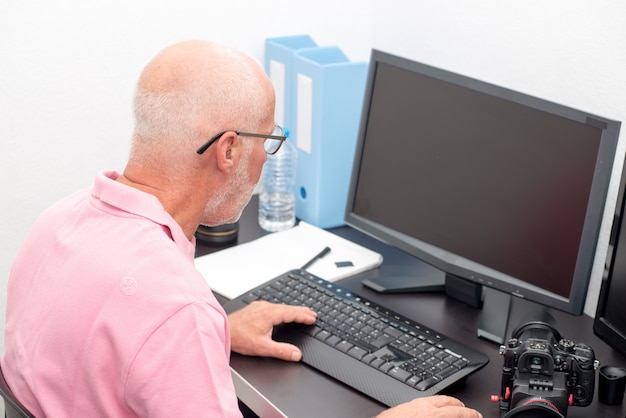 Reifer Mann, der mit Computer im Büro arbeitet