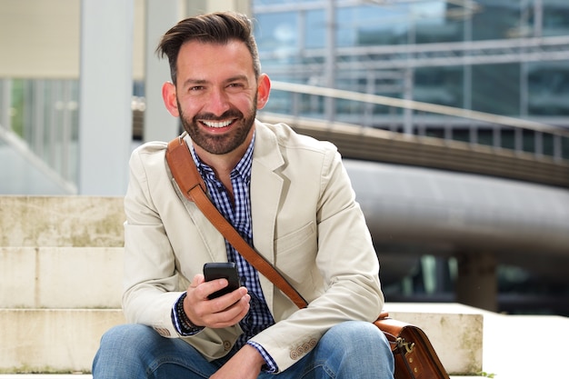 Reifer Mann, der mit Mobiltelefon lächelt