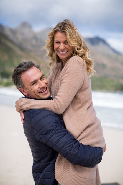 Reifer Mann, der reife Frau am Strand hält