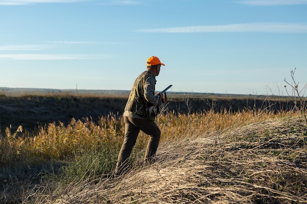 Reifer Mann Jäger mit Waffe beim Gehen auf dem Feld