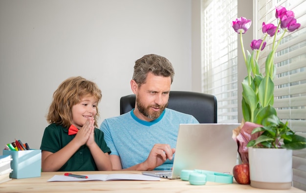 Reifer Mann, Lehrer oder Vater, der dem kleinen Sohn bei den Schulhausaufgaben auf Computer-E-Learning hilft