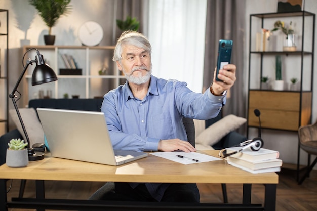 Reifer Mann macht Selfie mit erhobenem Finger im Heimbüro