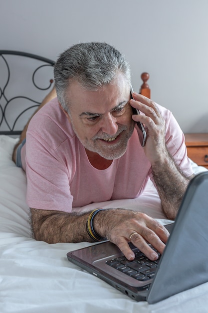 Reifer Mann mit Bart, der im Bett arbeitet