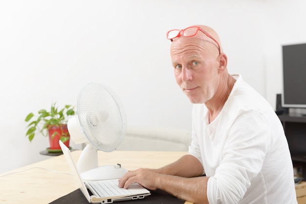 Reifer Mann mit einem Laptop im Haus