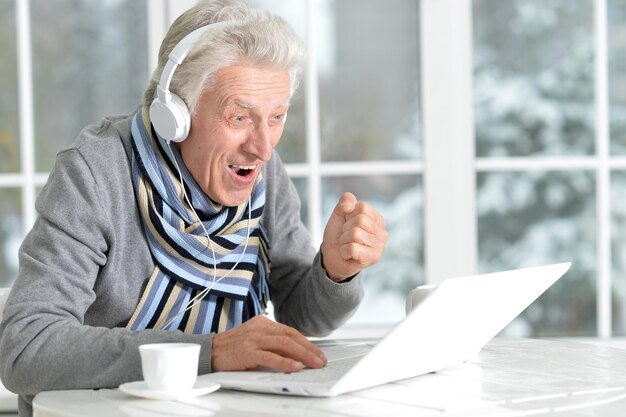 Reifer Mann mit Laptop, sitzt am Fenster