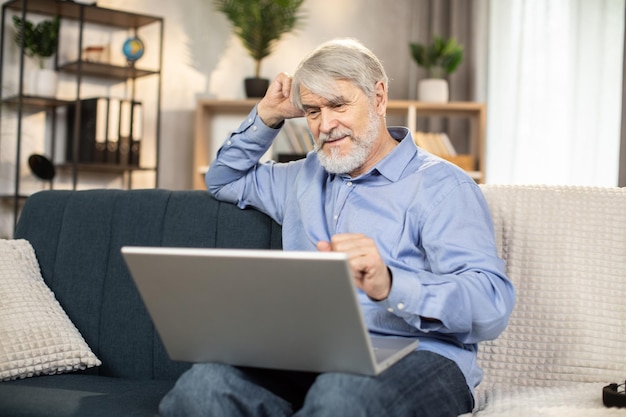 Reifer Mann schaut sich zu Hause online über Laptop Filme an