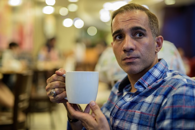 Reifer persischer Mann, der sich im Kaffeehaus entspannt