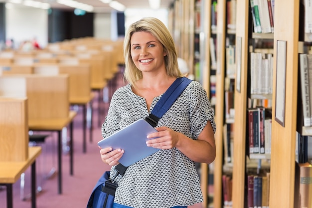 Reifer Student, der in der Bibliothek mit Tablette studiert