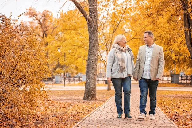 Reifes Paar, das im Park am Herbsttag geht