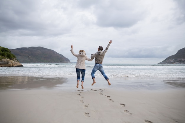 Reifes Paar, das in Luft am Strand springt